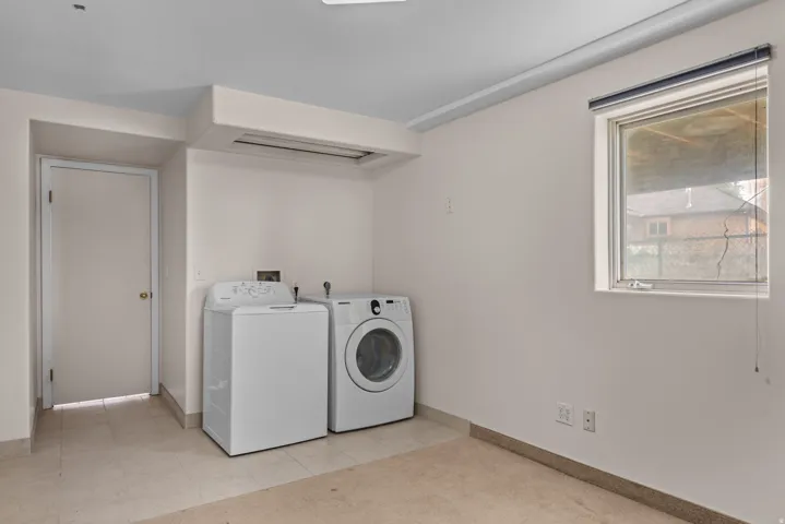 Dedicated laundry area featuring a window, light wall paint, and a combination of carpet and tile flooring