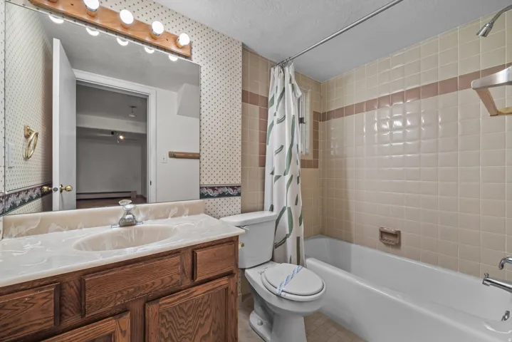 Bathroom featuring a wood-finish vanity with a built-in sink, a large wall-mounted mirror, and a multi-bulb light fixture