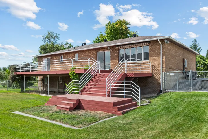 Rear exterior featuring a brick facade, multi-level red deck with white railings, and a sliding glass door