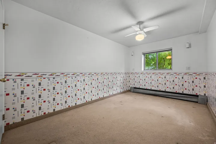 Room featuring a ceiling fan with integrated lighting, a window with exterior foliage visible, and baseboard heating