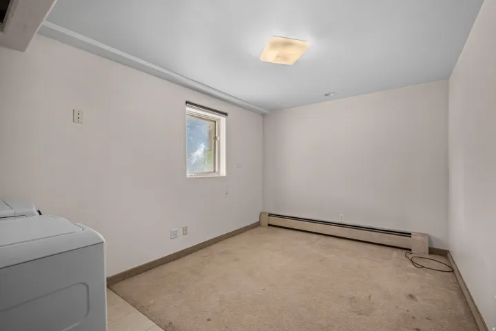 Versatile room featuring a flush-mount ceiling light, a single window, baseboard heating, and light-toned wall finishes