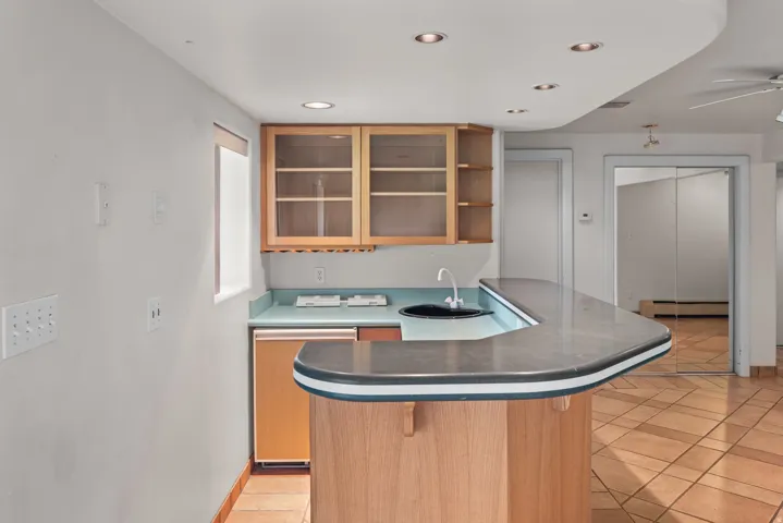 Built-in bar featuring wood-finish cabinetry, a built-in sink, and a refrigerator