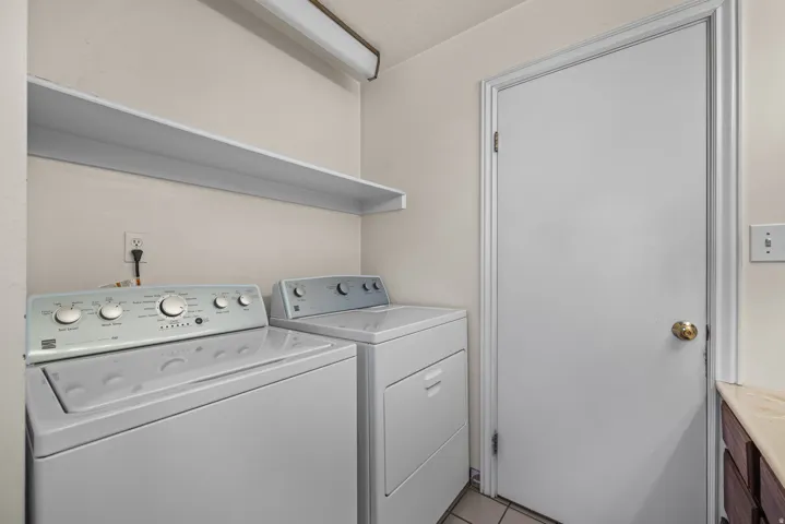 Laundry area featuring a top-load washing machine, front-load dryer, and an overhead storage shelf