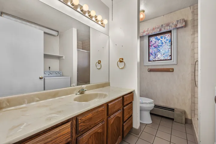 Dual sink vanity featuring wood-finish cabinetry and a stone-look countertop
