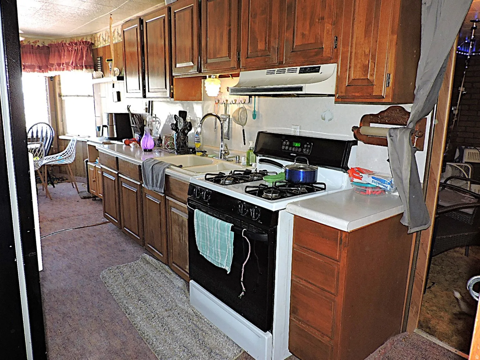 Kitchen featuring wood cabinetry, a built-in double basin sink, and a four-burner gas range