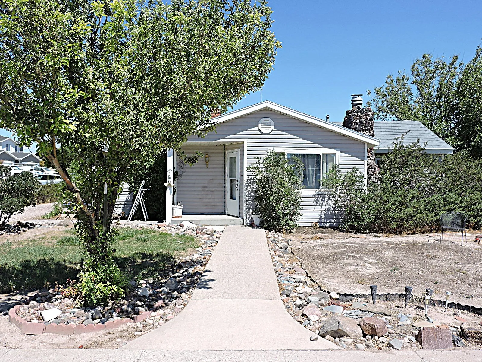 Single-story residence featuring light gray siding and a concrete walkway