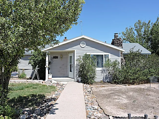 Ranch-style residence featuring light gray siding and a stone chimney