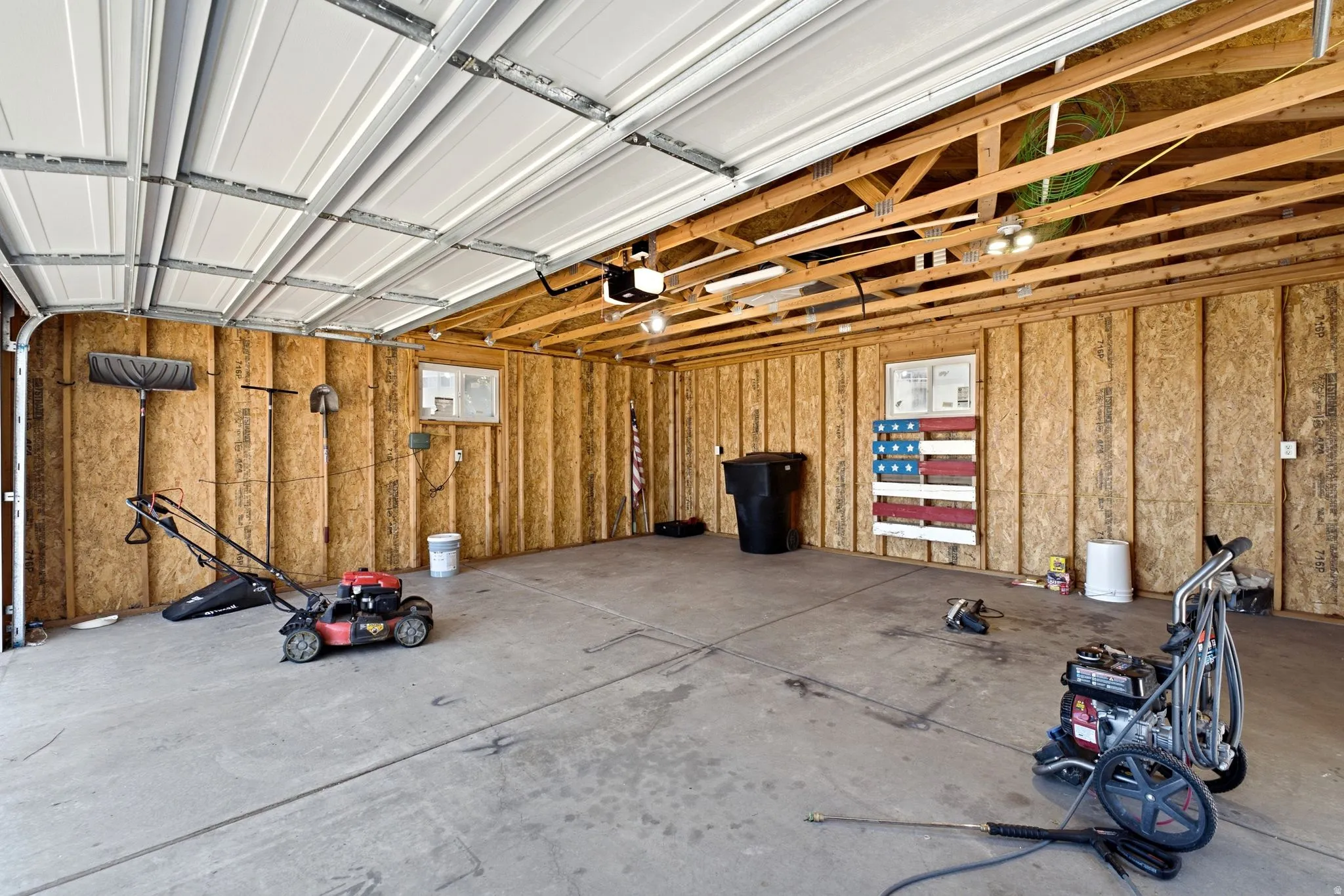 Spacious garage featuring concrete flooring and exposed wood framing