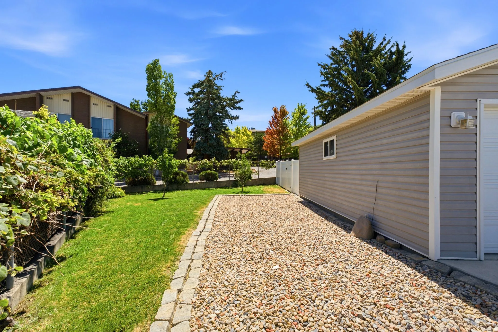 Gravel driveway with paver edging, leading to a gray vinyl-sided garage