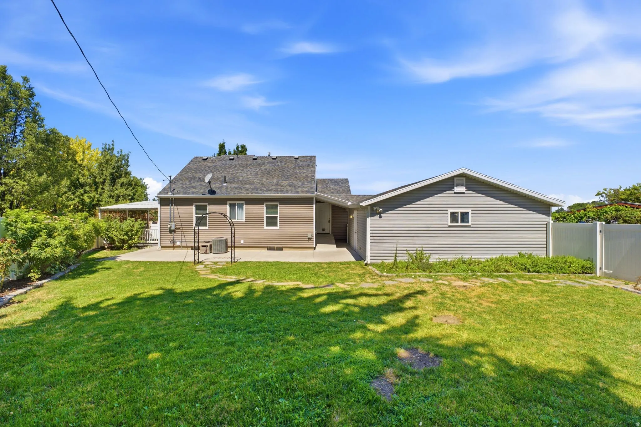 Expansive green lawn with a concrete patio and a detached auxiliary building featuring siding