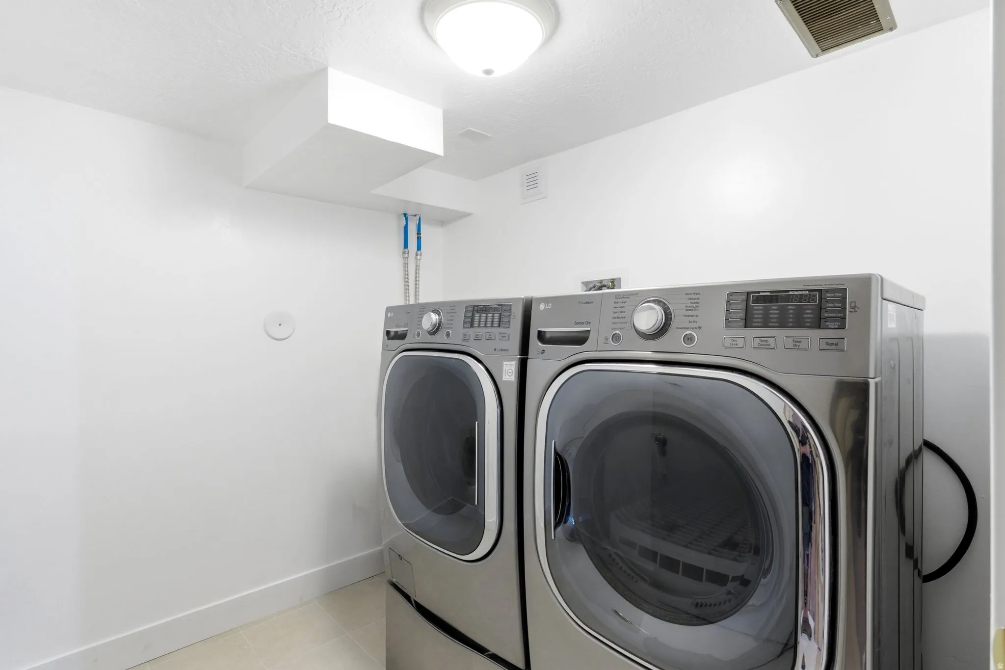 Dedicated laundry space featuring a front-loading washer and dryer, ceiling-mounted light fixture, and white painted walls