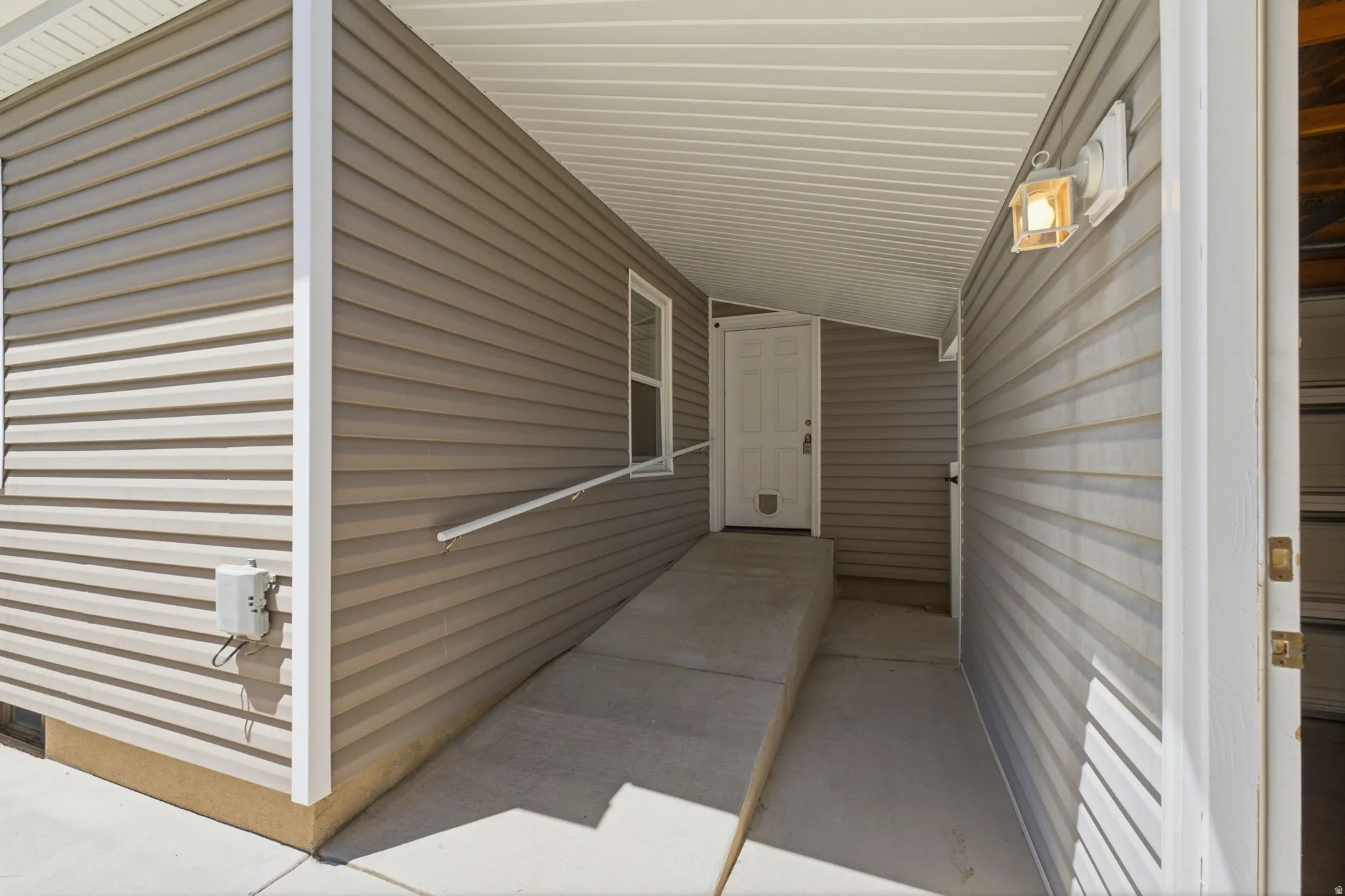 Covered entryway featuring tan horizontal siding and a white paneled door