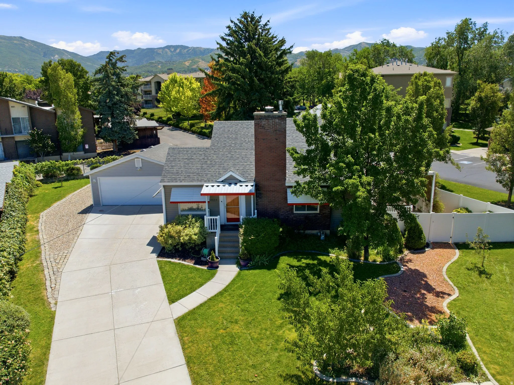 Traditional-style home featuring a prominent brick chimney, an attached garage, and a concrete driveway