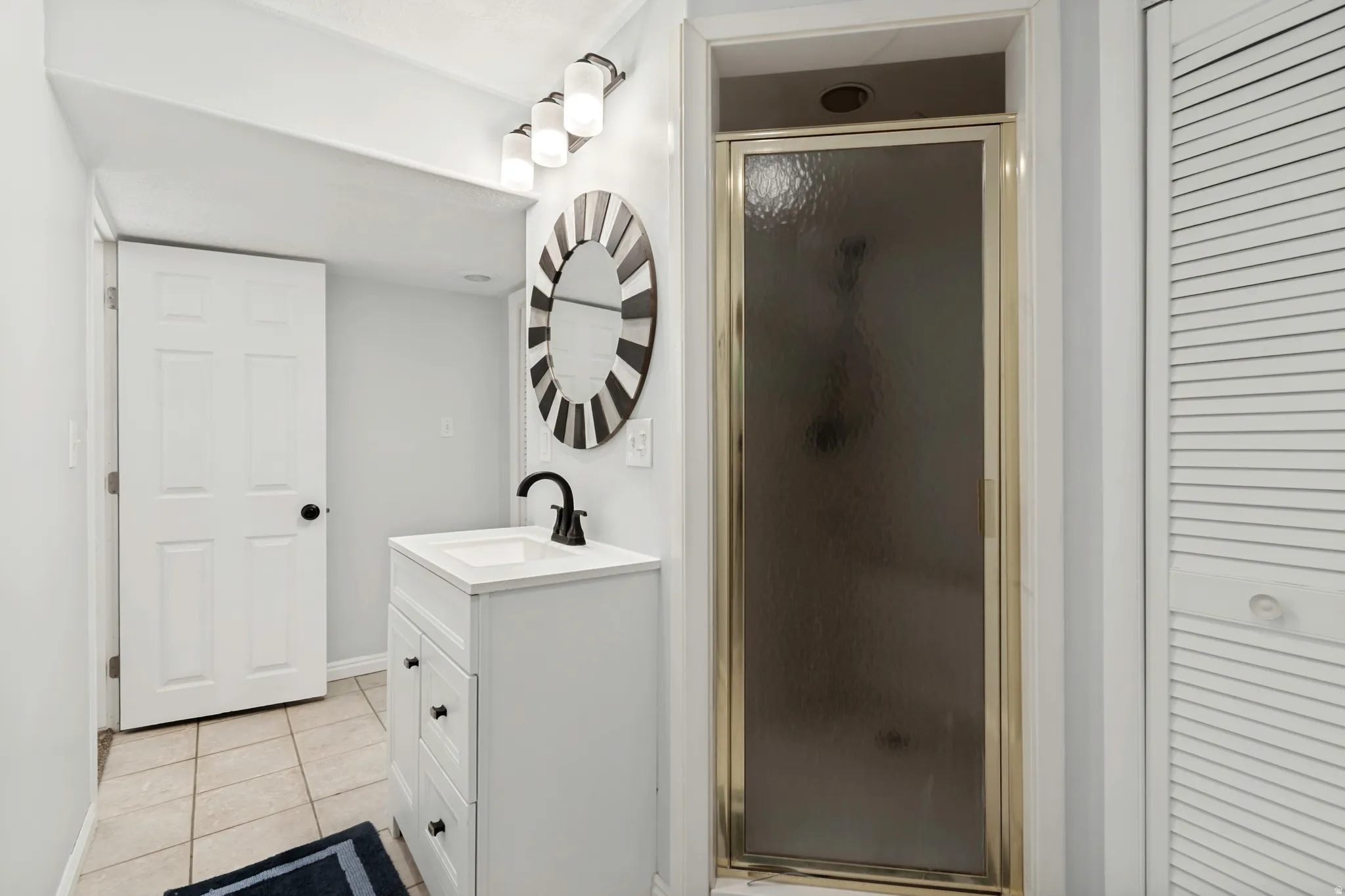 Bathroom featuring a white vanity with integrated sink, black matte faucet, and round decorative mirror