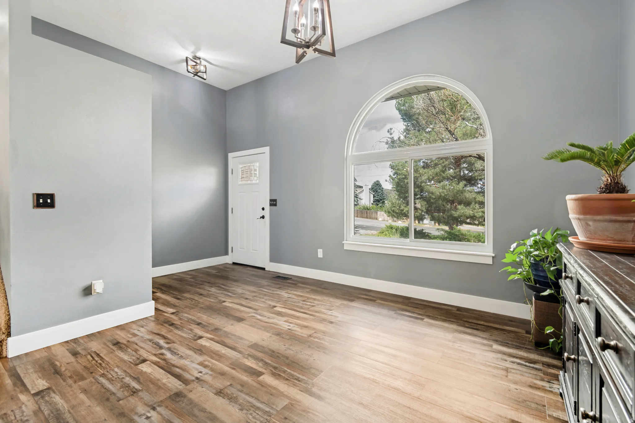 Entryway featuring an arched window, wood-finish flooring, and contemporary pendant lighting