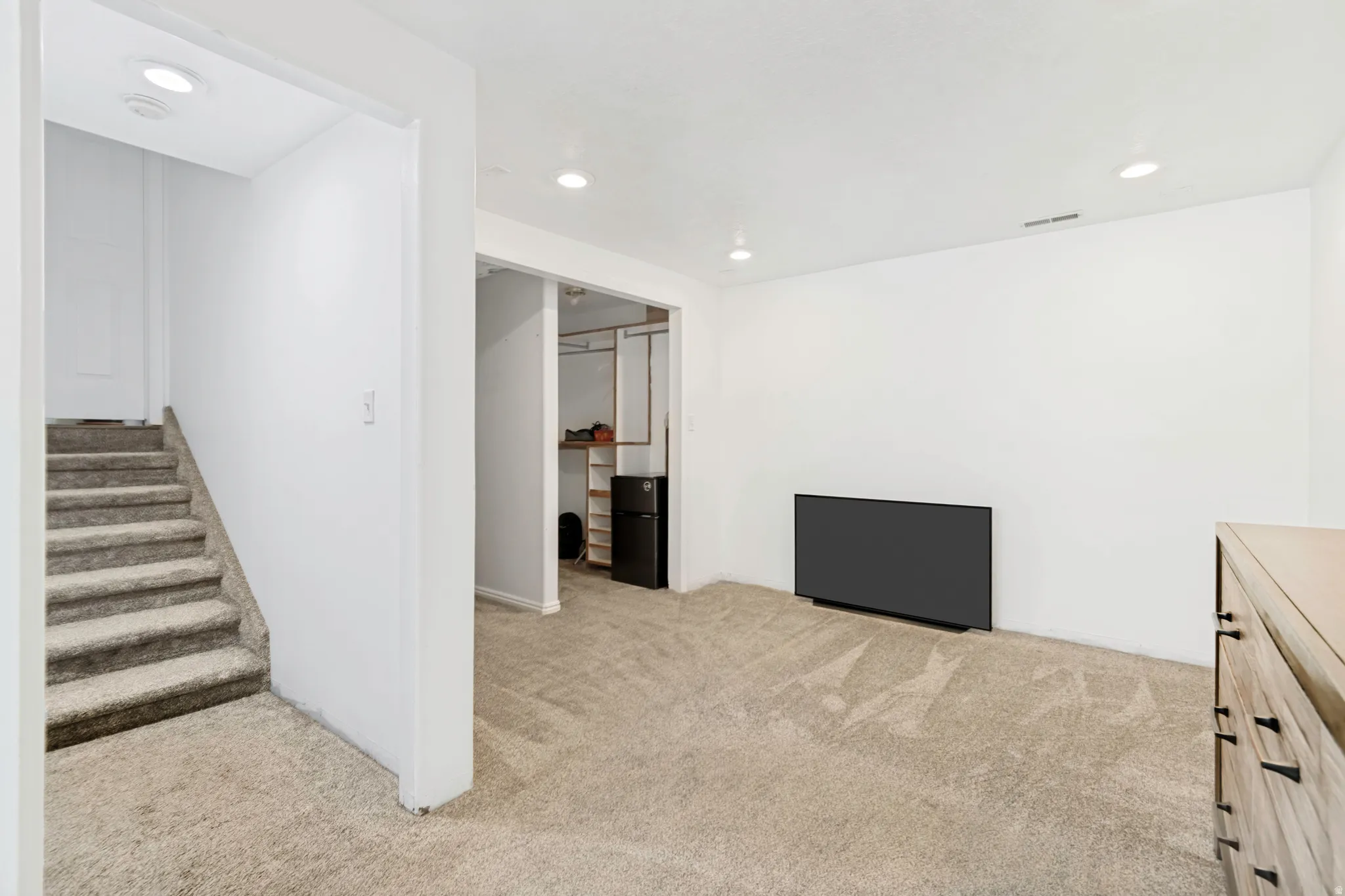 Carpeted lower level room featuring recessed lighting, a built-in closet system, and a beverage refrigerator