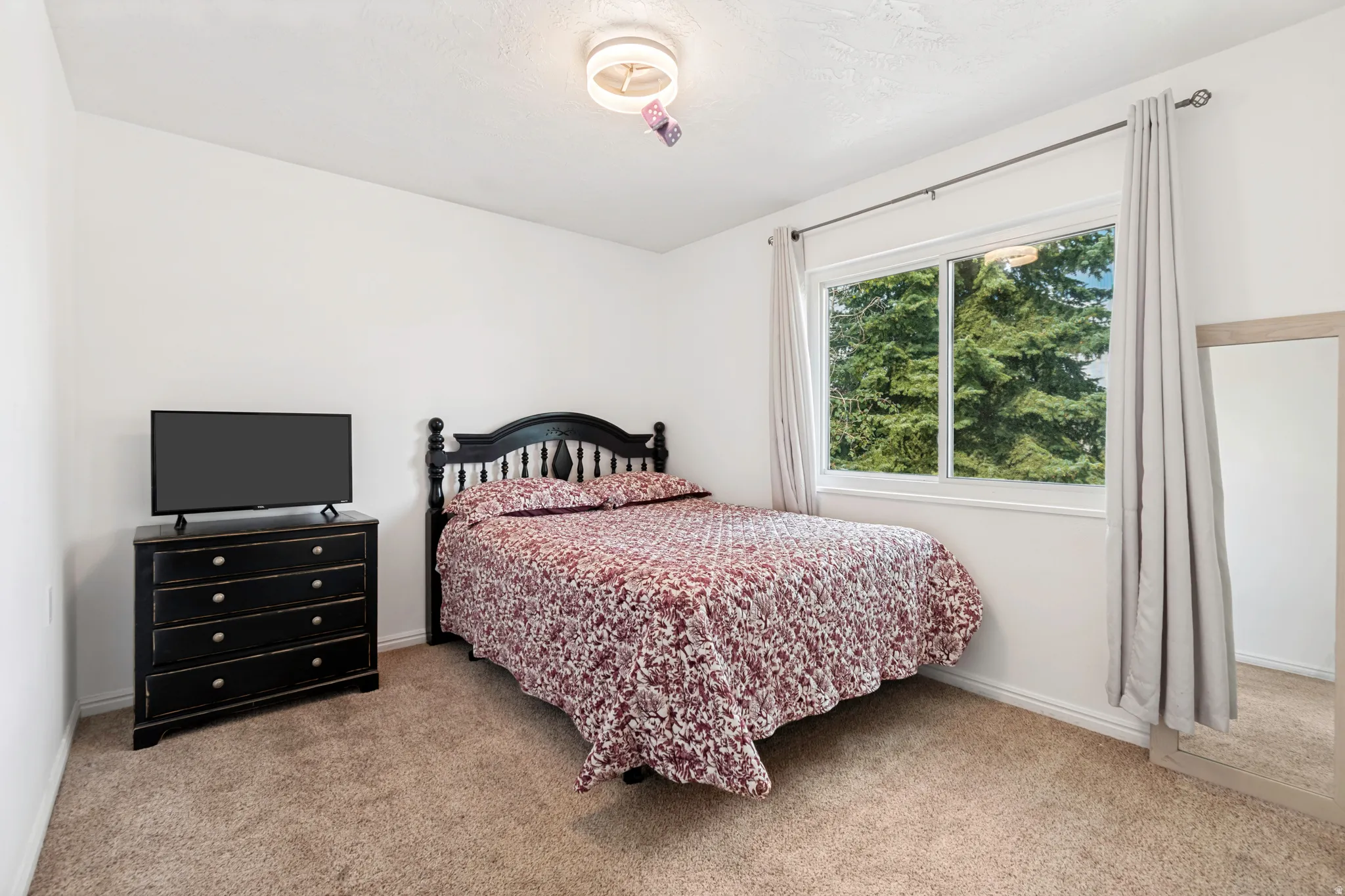 Carpeted room featuring a large window, a ceiling-mounted light fixture, and white wall finishes
