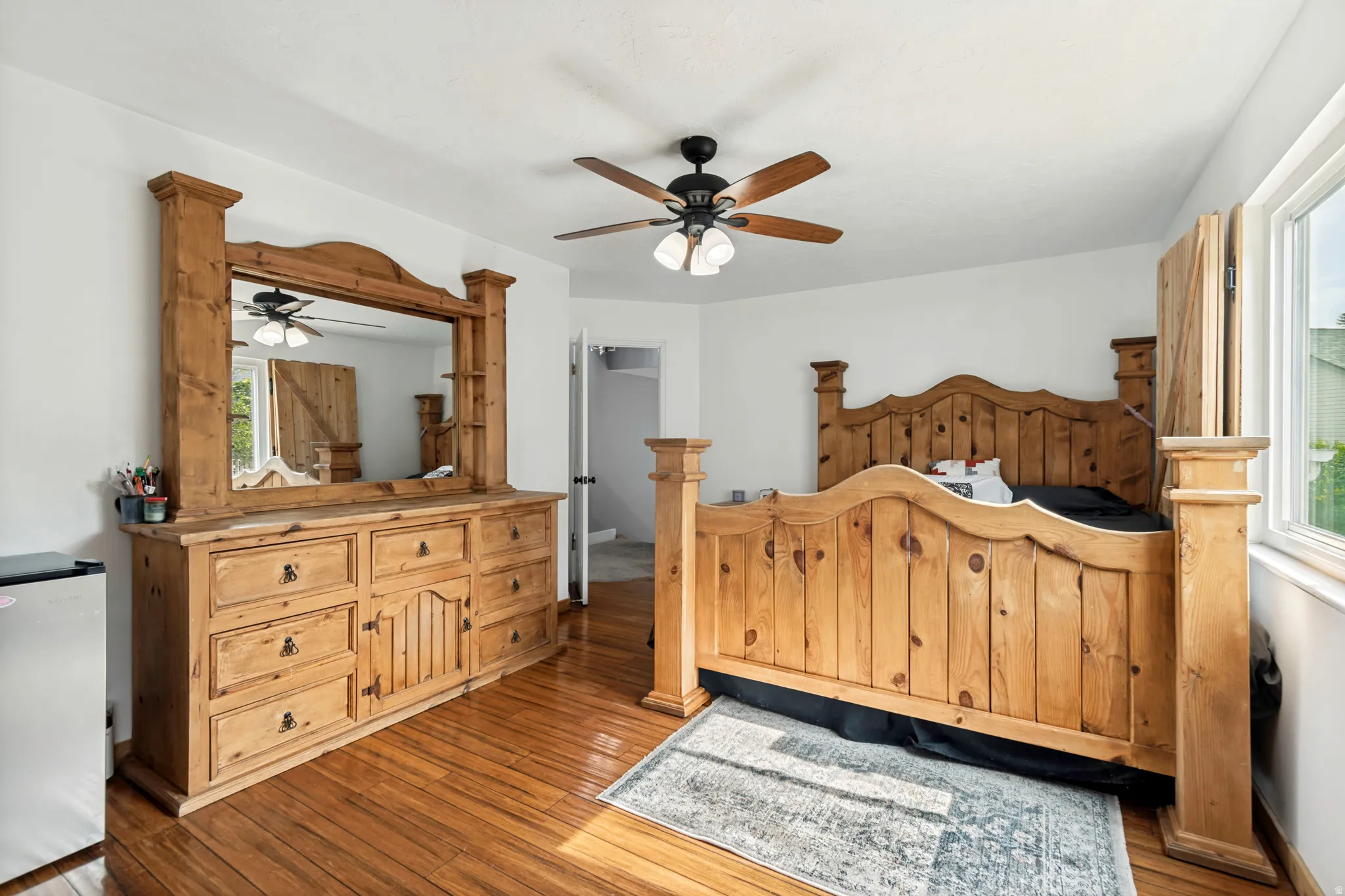 Room featuring wood-finish flooring, a ceiling fan with integrated lighting, white walls, and a window with natural light