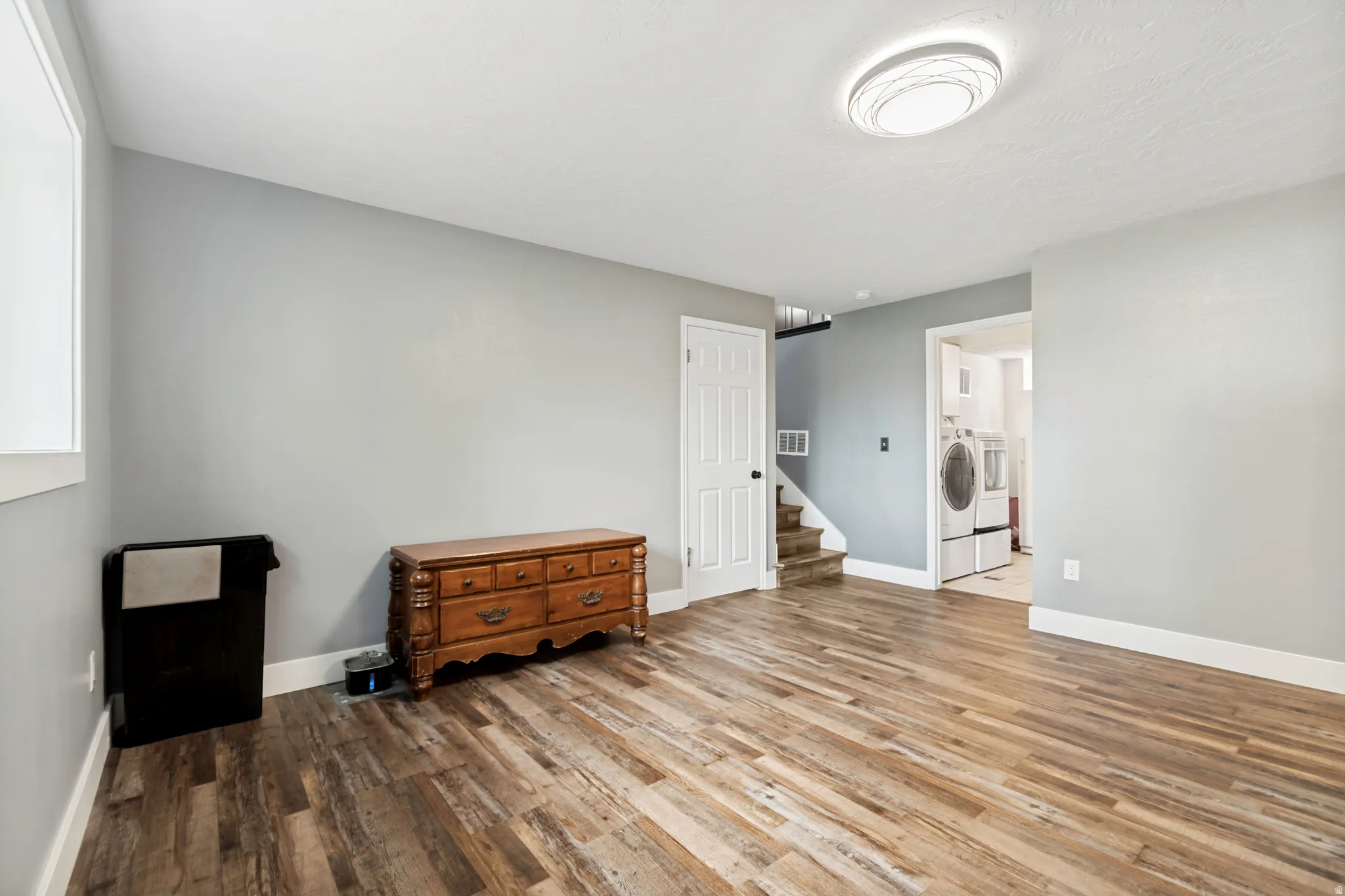 Spacious room featuring wood-finish flooring, light gray walls, and white trim