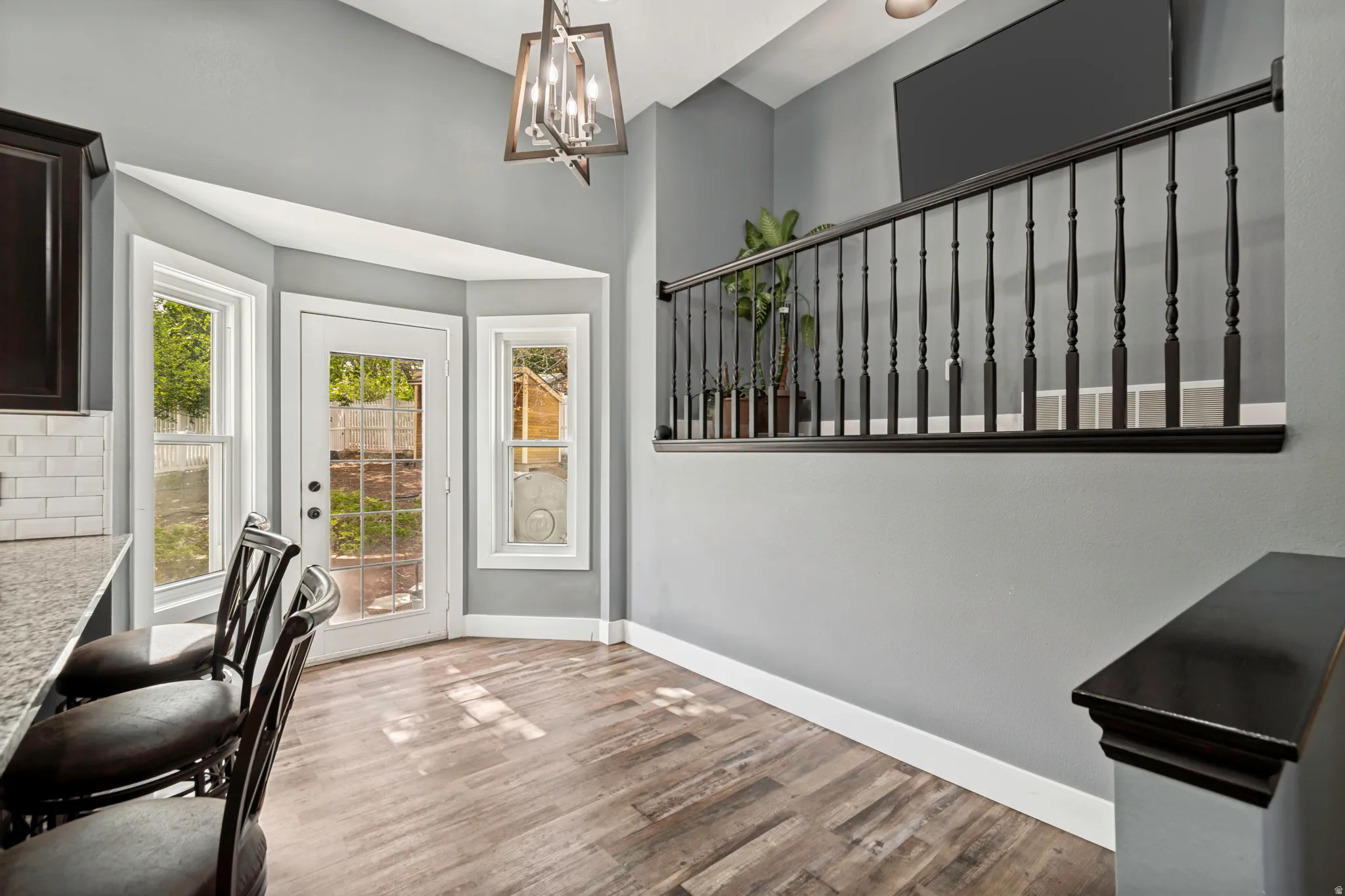 Kitchen eating area featuring wood-finish flooring, a white subway tile backsplash, and a granite countertop
