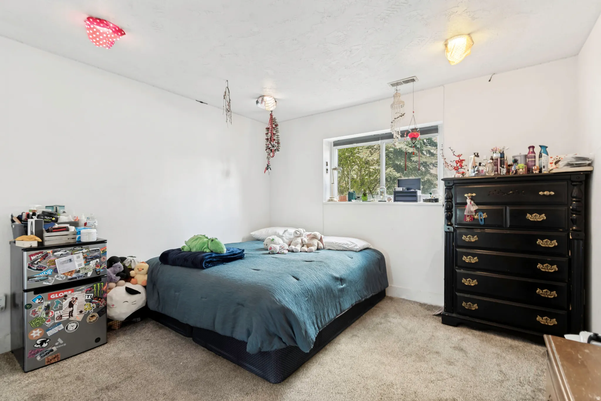 Carpeted bedroom featuring white walls and a large window providing natural light