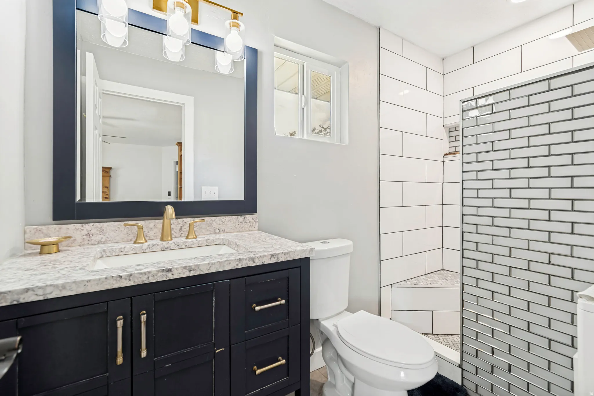 Bathroom featuring a dark wood-finish vanity with a light speckled countertop, an undermount sink, and brass-finish fixtures