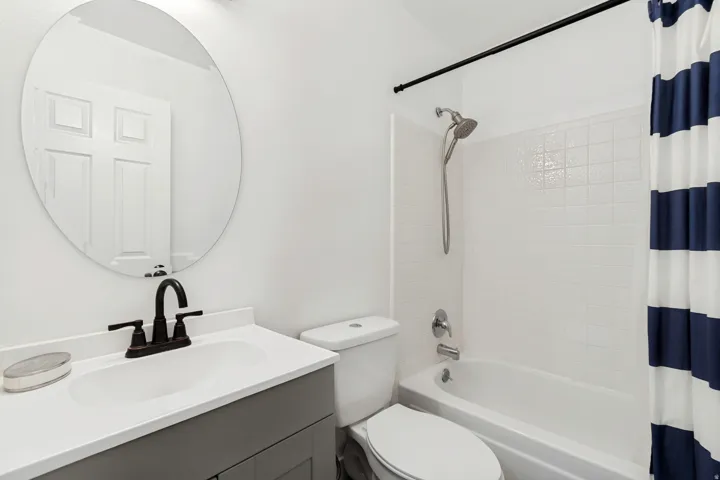 Bathroom featuring a vanity with an integrated sink, dark bronze faucet, and a circular mirror