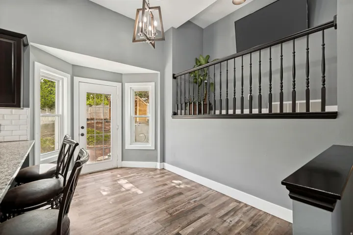 Kitchen eating area featuring wood-finish flooring, a white subway tile backsplash, and a granite countertop