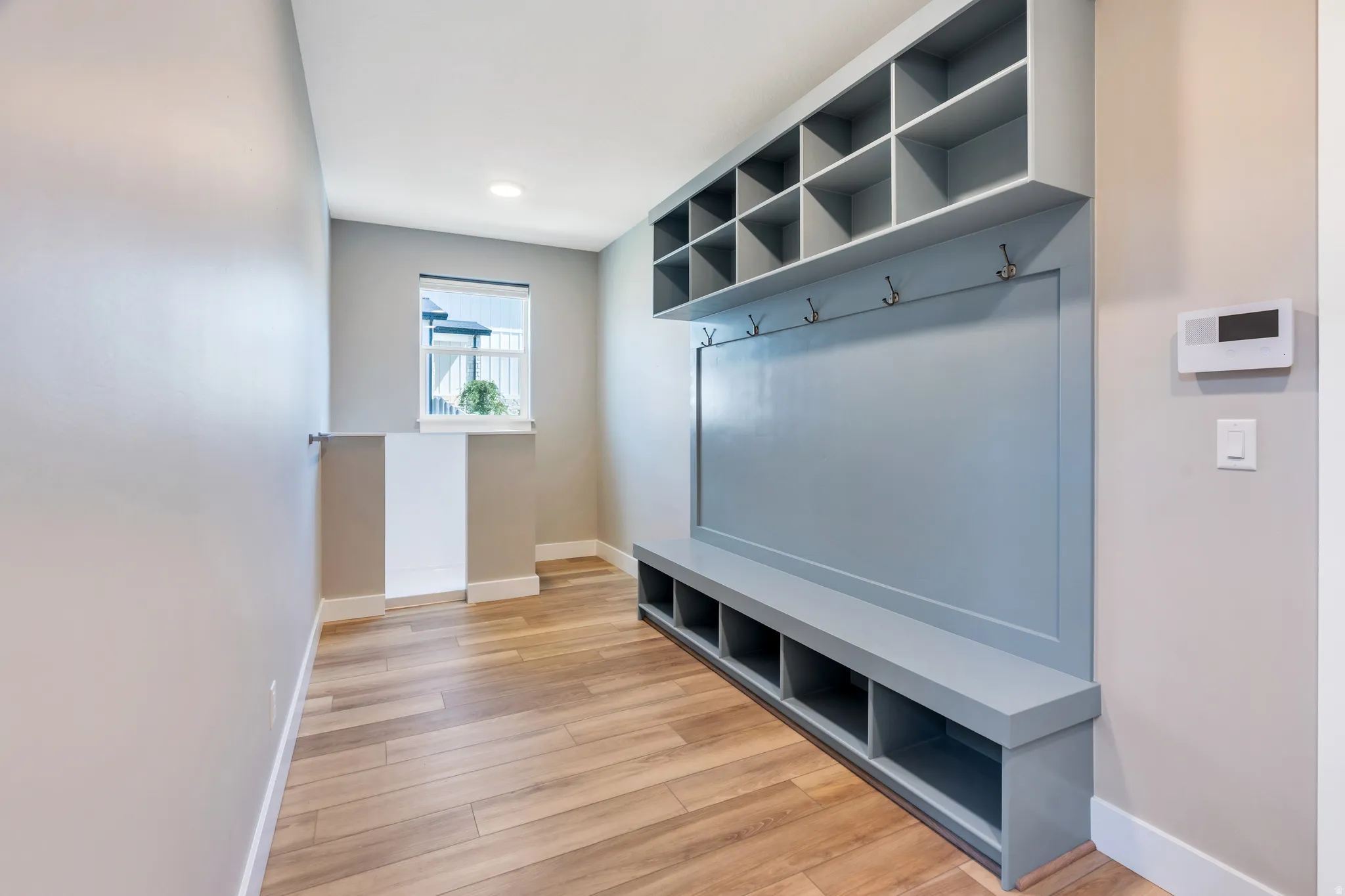 Dedicated mudroom with built-in storage unit and open shelving, integrated bench seating, and coat hooks