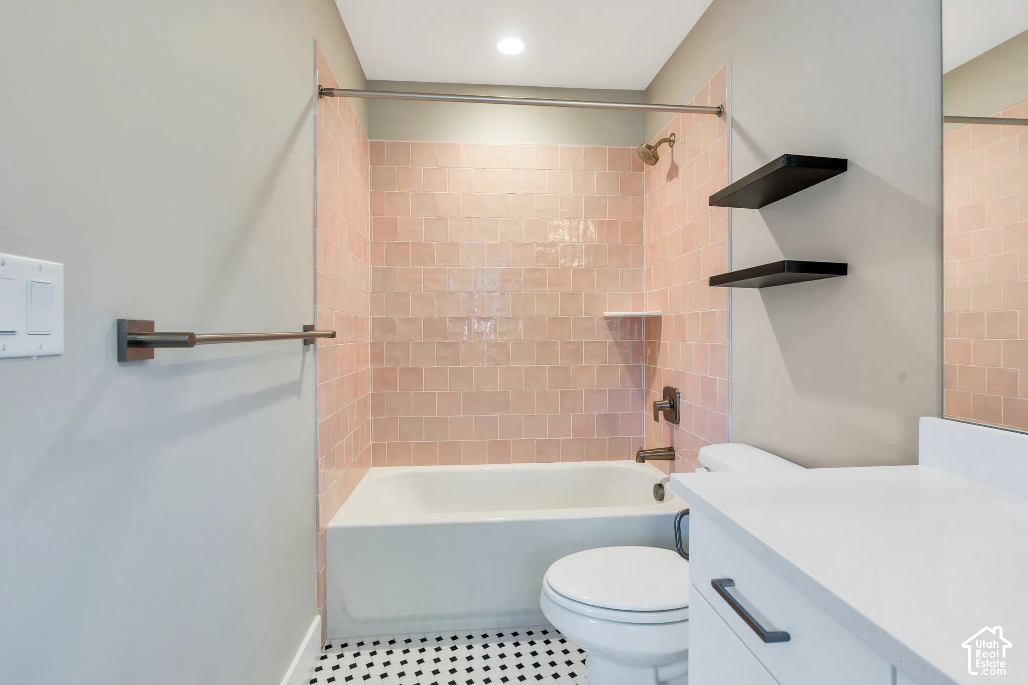 Bathroom featuring a tub/shower combination with pink square tile surround, a built-in shower niche, and a bronze shower fixture