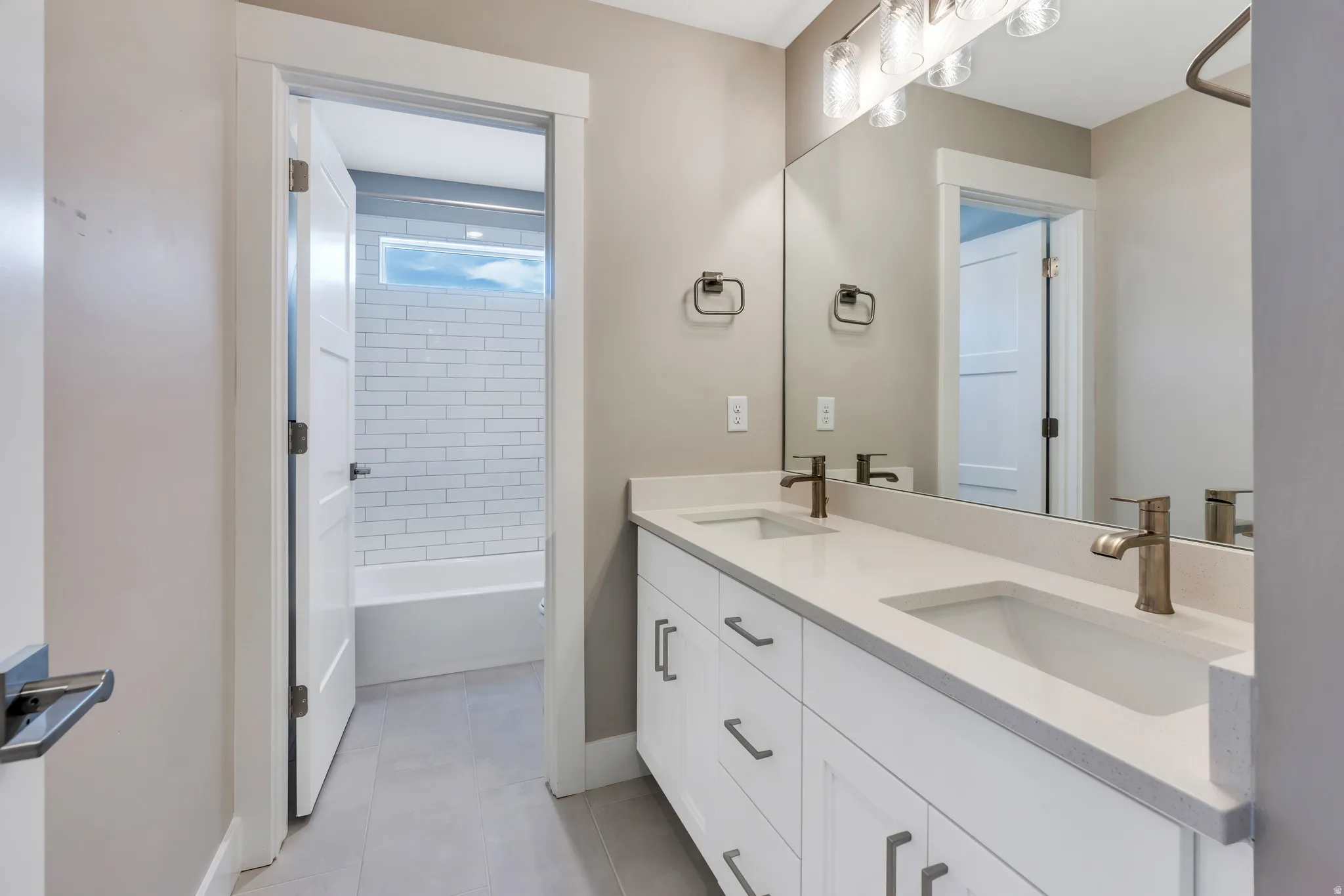 Double vanity with light countertops and undermount sinks, bronze-finish faucets, and a large wall-mounted mirror