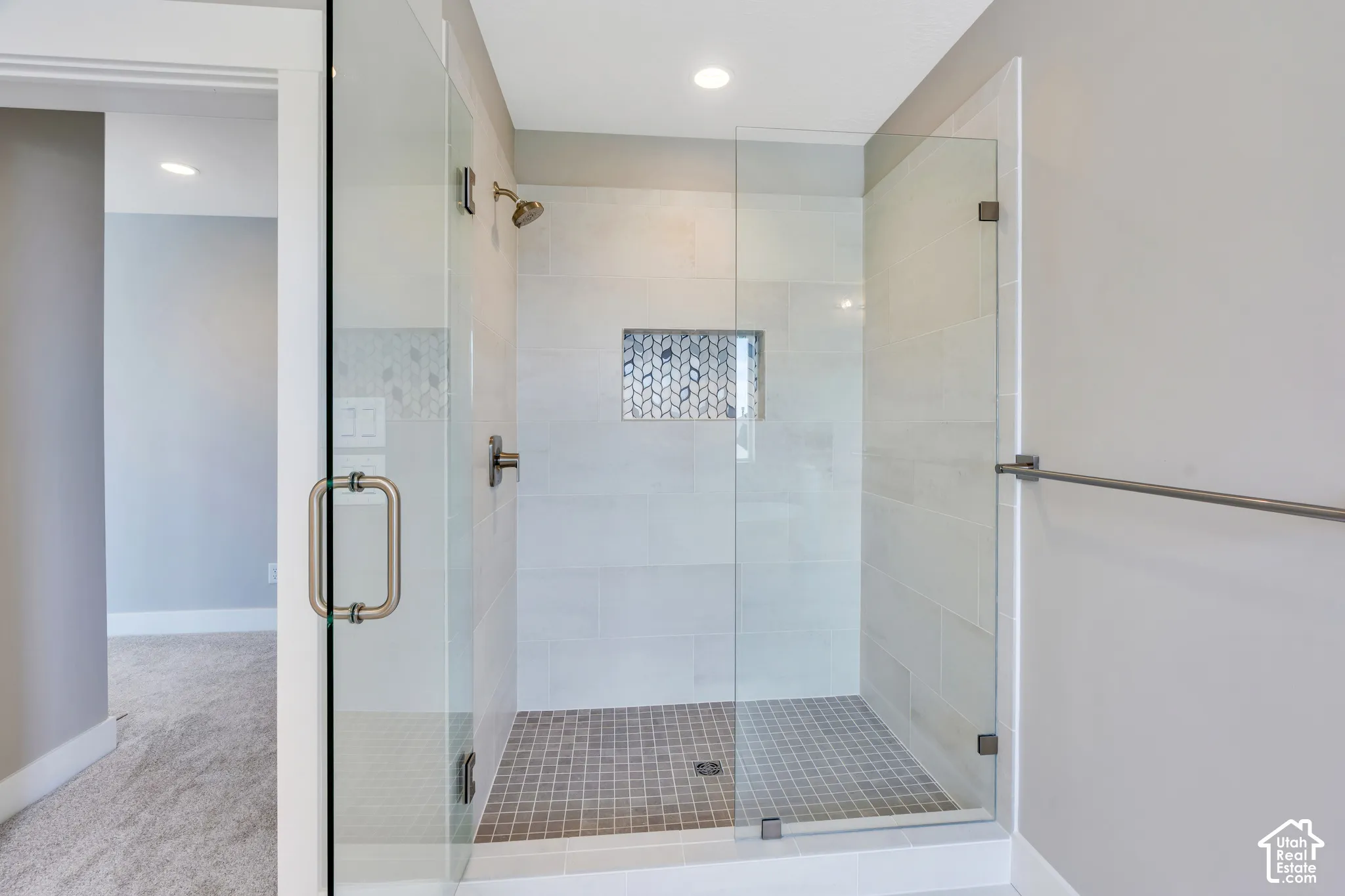 Primary bathroom with a glass-enclosed walk-in shower featuring large format wall tiles and a mosaic tile niche