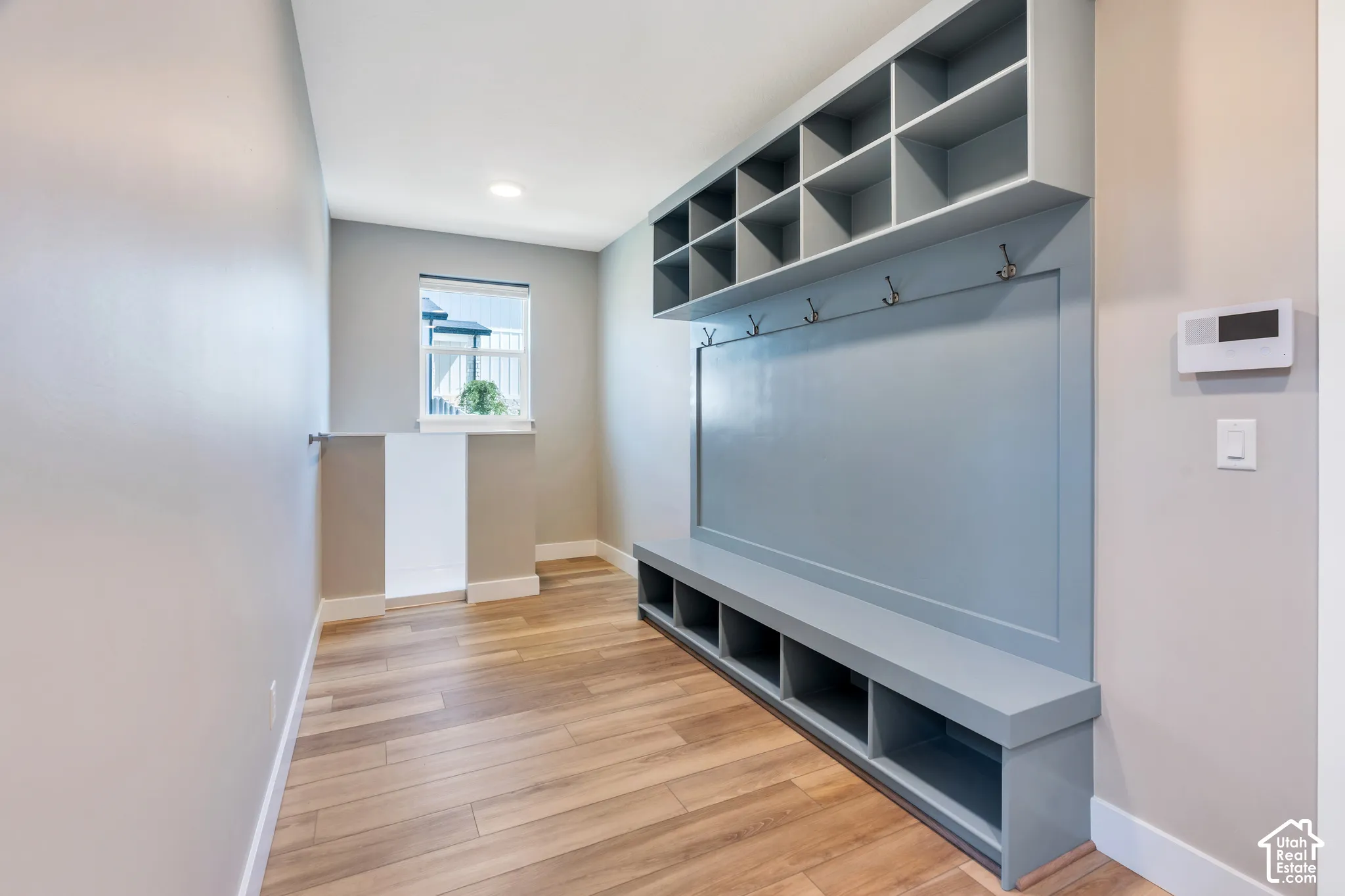 Dedicated mudroom with built-in storage unit and open shelving, integrated bench seating, and coat hooks