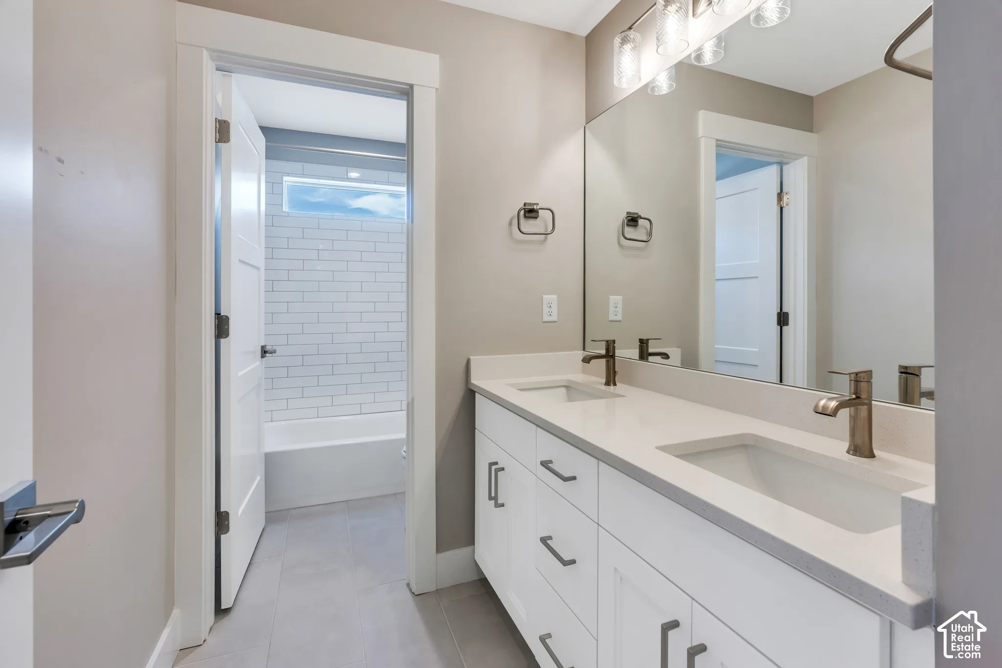 Double vanity with light countertops and undermount sinks, bronze-finish faucets, and a large wall-mounted mirror