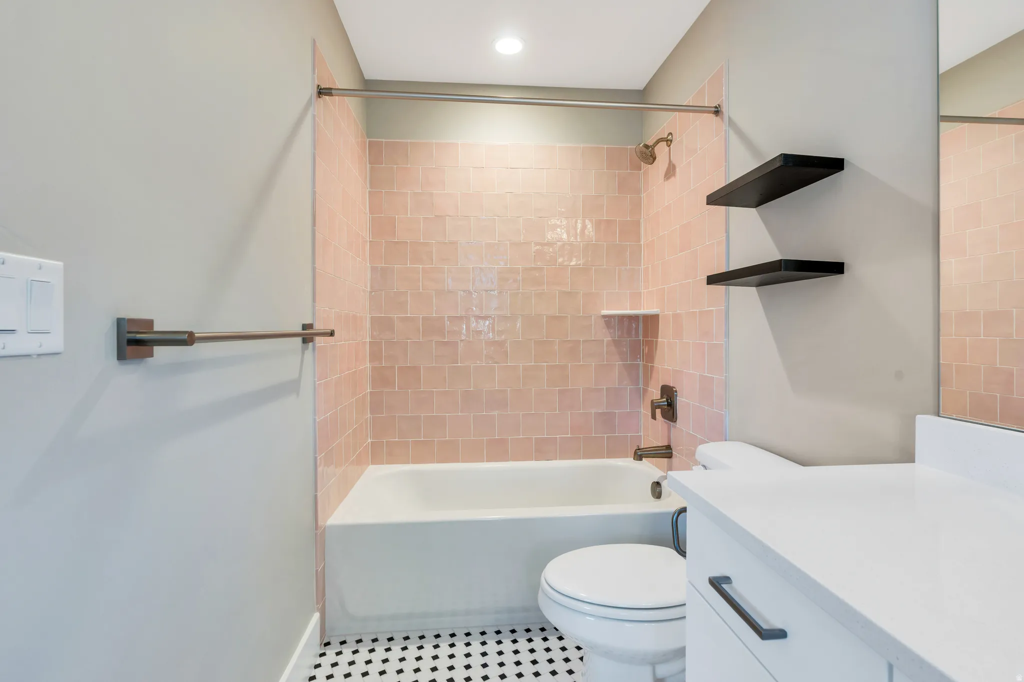 Bathroom featuring a tub/shower combination with pink square tile surround, a built-in shower niche, and a bronze shower fixture