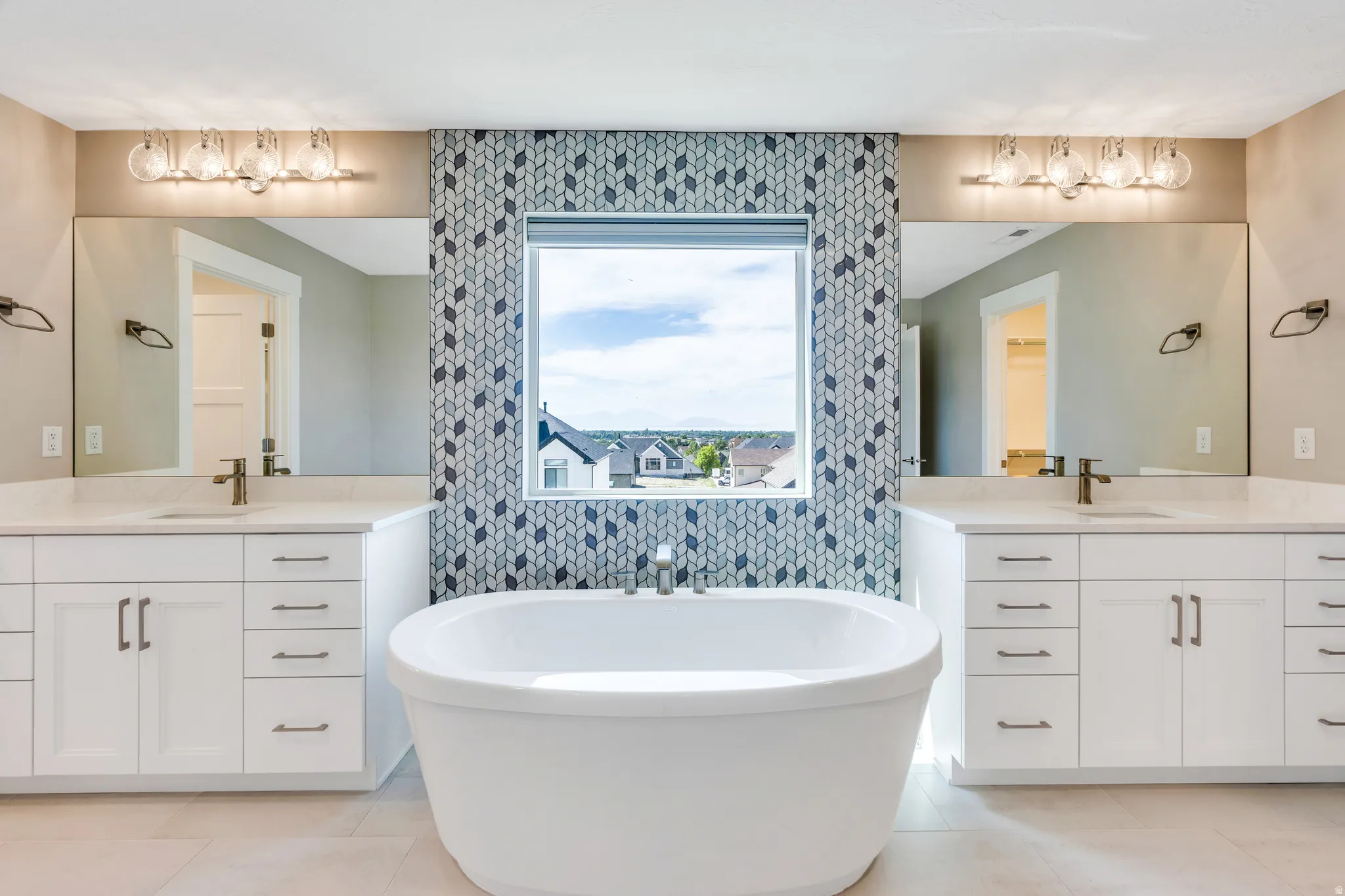 Primary bathroom with a freestanding soaking tub with a patterned tile accent wall surrounding the window