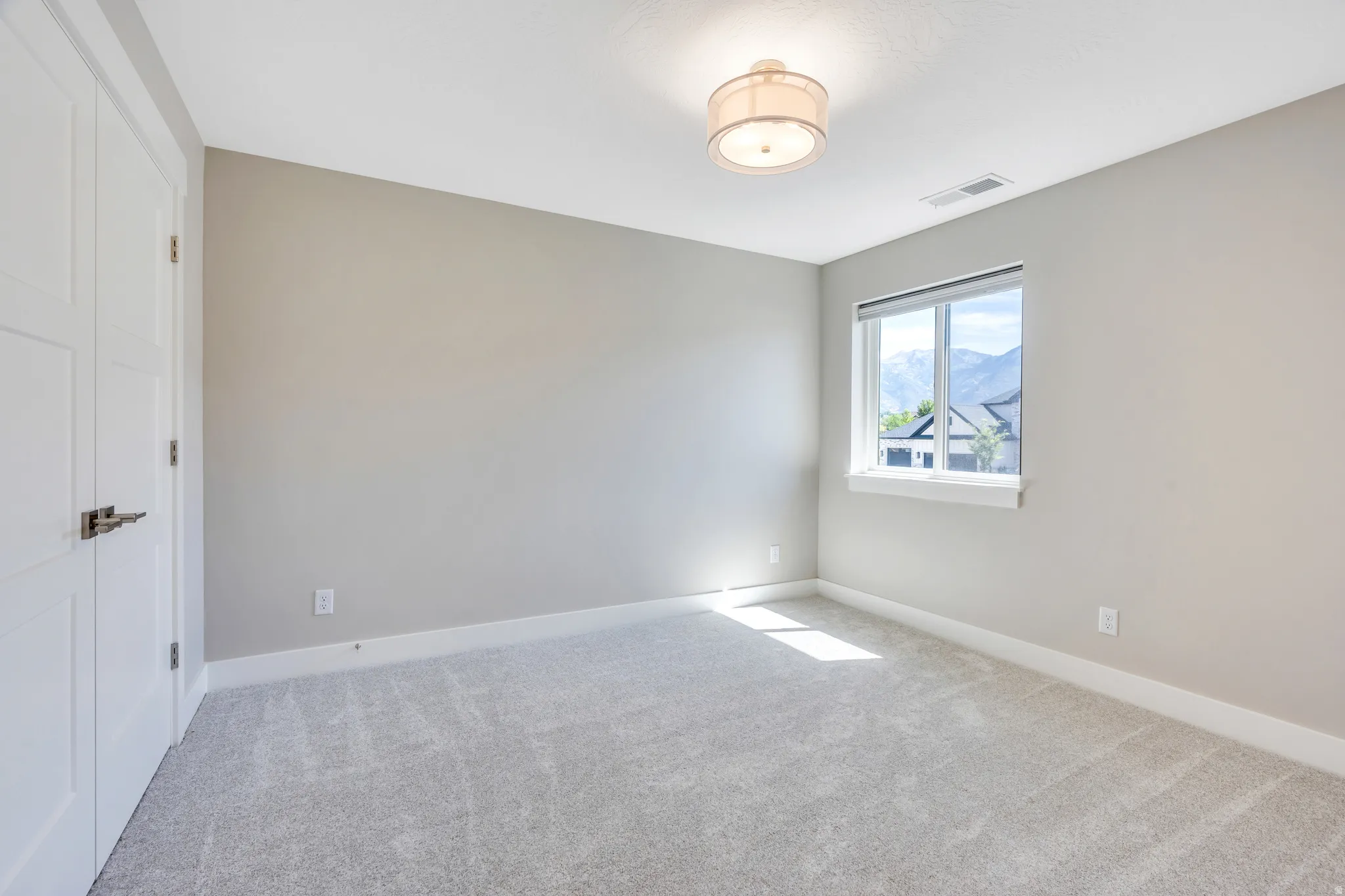 Neutral-toned room featuring a single window, recessed lighting, and light-grey carpeting