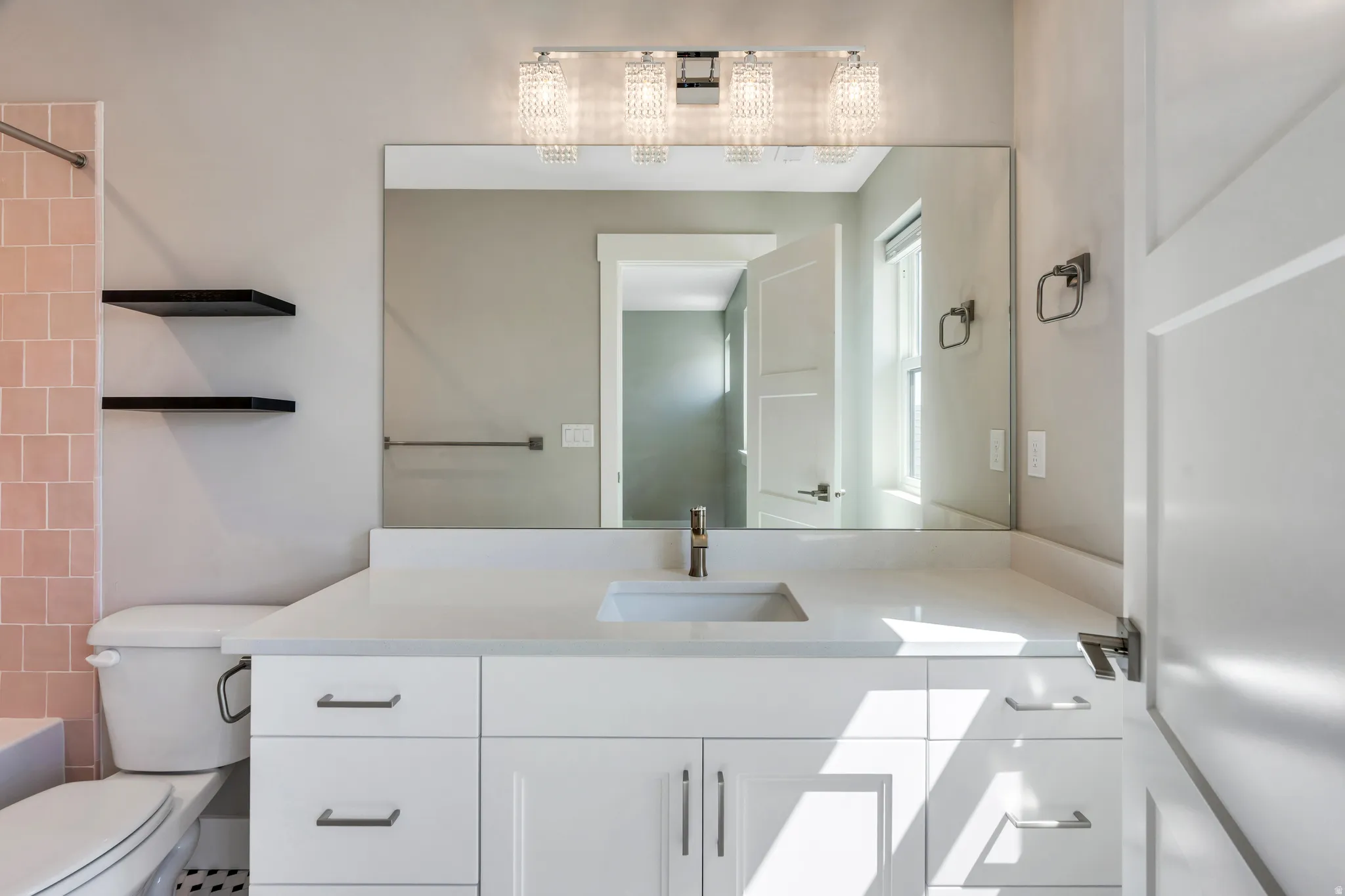 Bathroom featuring an expansive vanity with a white countertop, undermount sink, and brushed nickel faucet