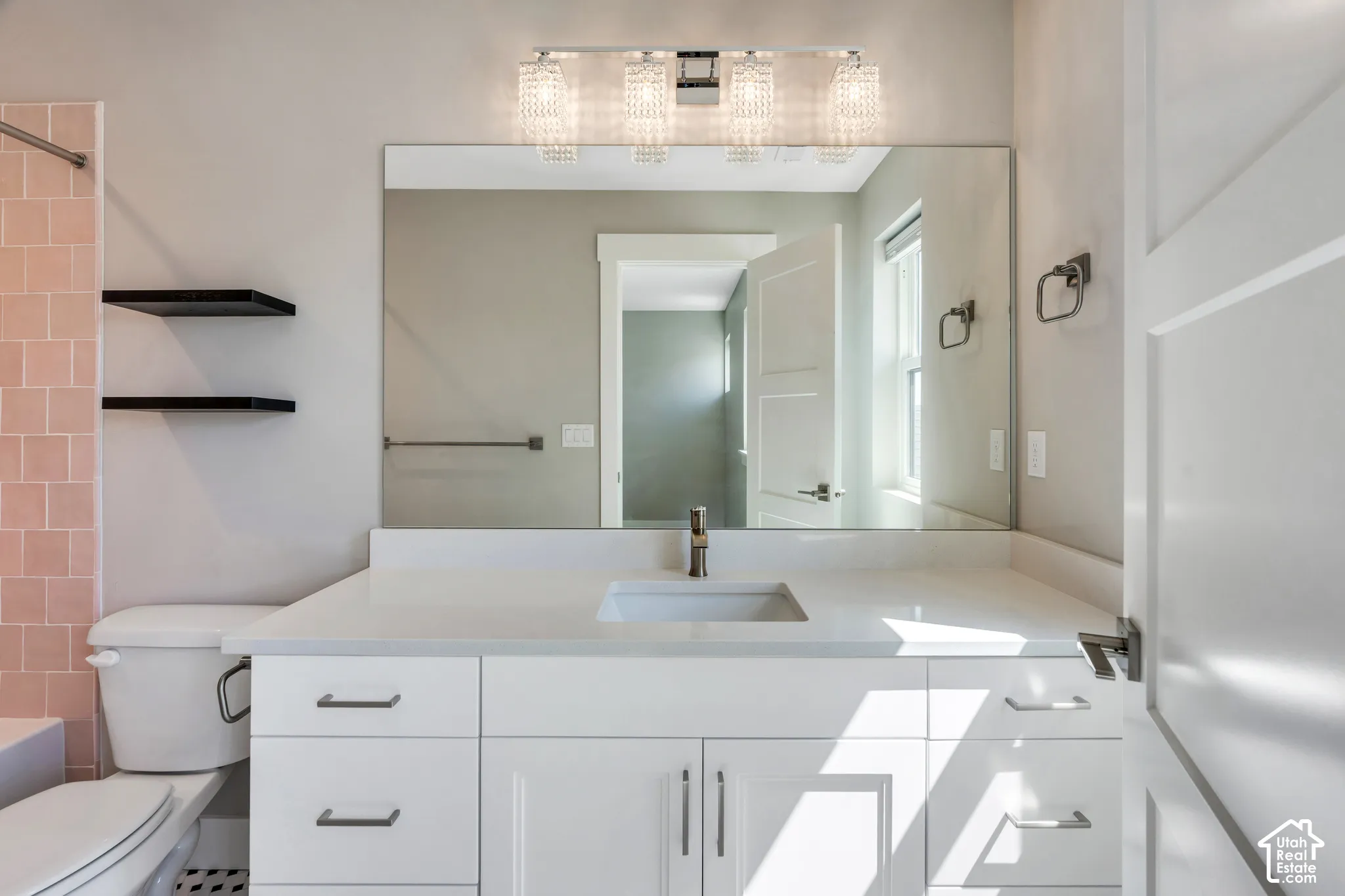 Bathroom featuring an expansive vanity with a white countertop, undermount sink, and brushed nickel faucet