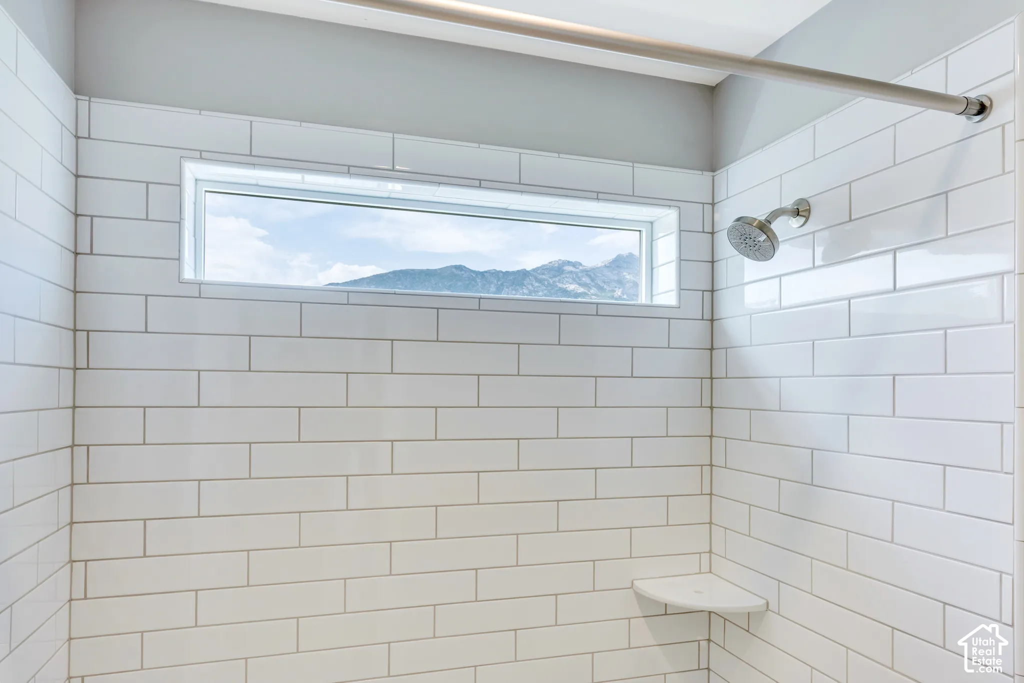 Shower with subway tile surround, featuring a transom window, built-in corner shelf, and brushed nickel shower head
