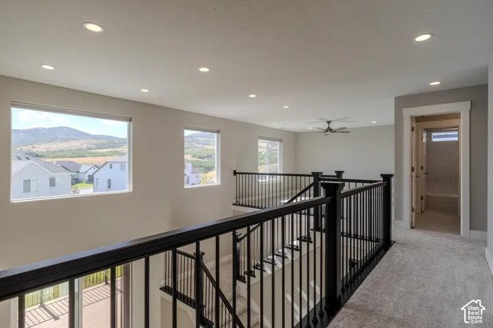 Upper-level landing featuring black wrought iron railing, recessed lighting, and wall-mounted ceiling fan