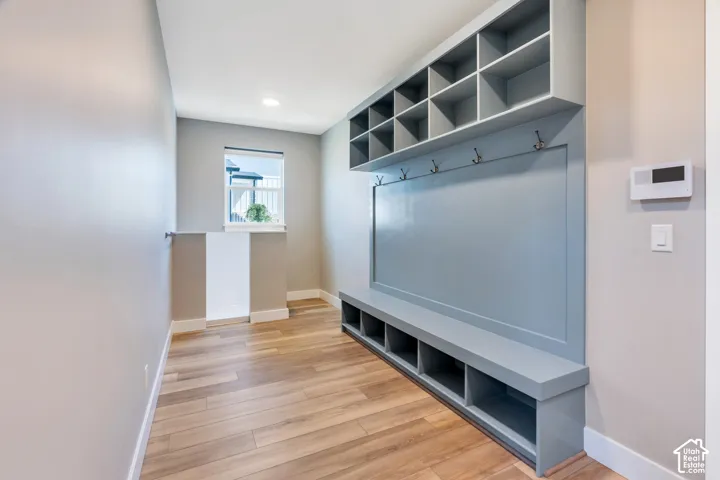 Dedicated mudroom with built-in storage unit and open shelving, integrated bench seating, and coat hooks