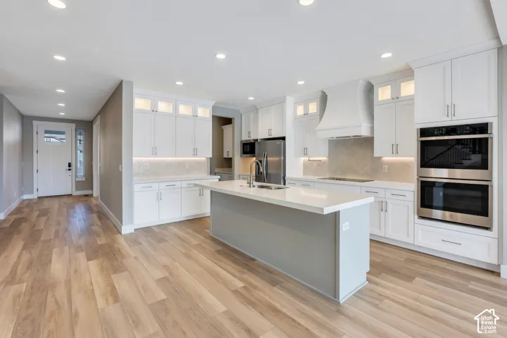 Open-concept kitchen featuring an expansive island with a light gray base, white countertop, and stainless steel sink