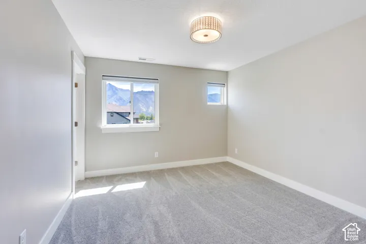 Spacious room with plush gray carpeting, two windows, and neutral wall paint