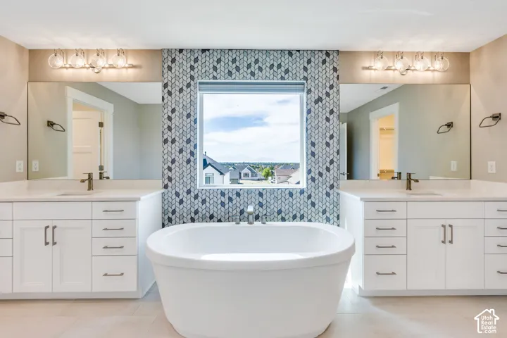 Primary bathroom with a freestanding soaking tub with a patterned tile accent wall surrounding the window