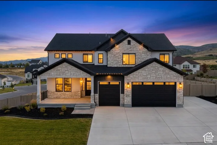 Contemporary two-story residence featuring a stone and stucco exterior, prominent black-framed windows, and a black shingled roof
