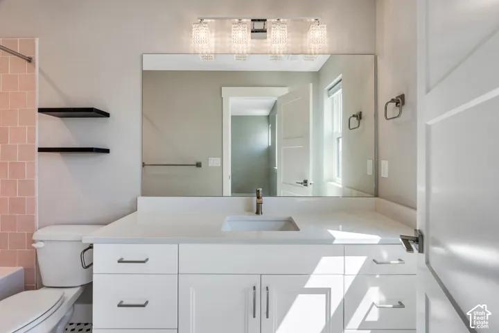 Bathroom featuring an expansive vanity with a white countertop, undermount sink, and brushed nickel faucet