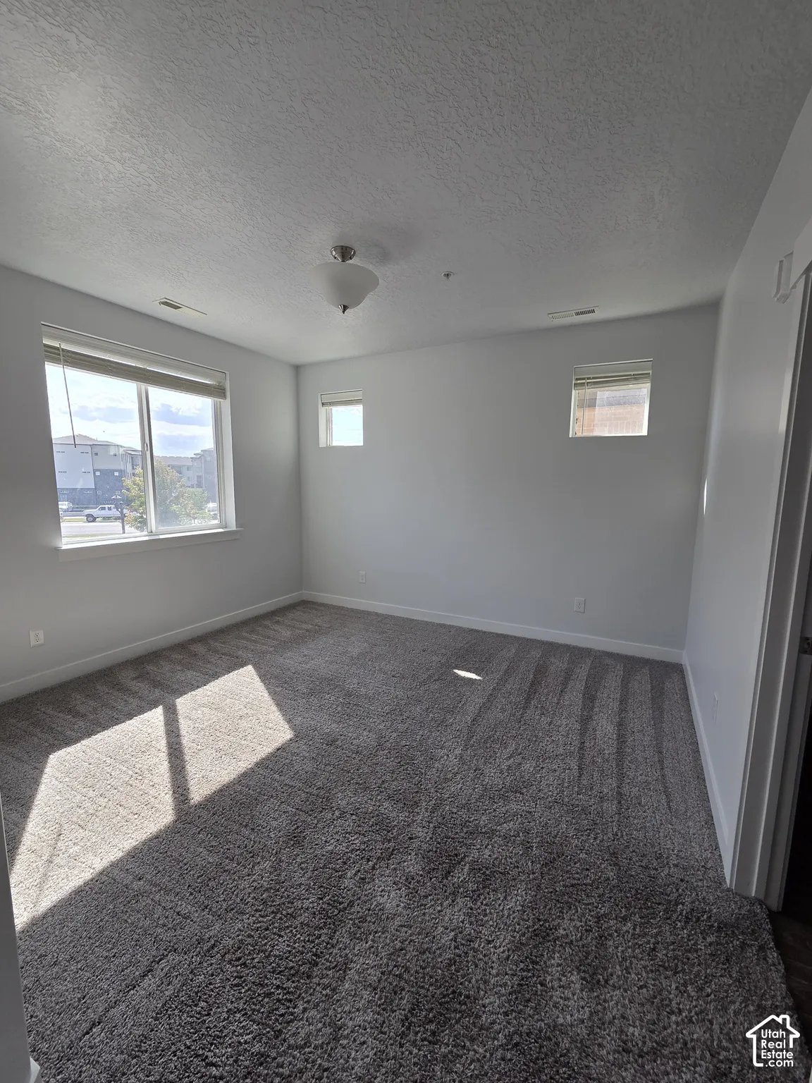 Spacious room featuring neutral grey walls and plush grey carpet