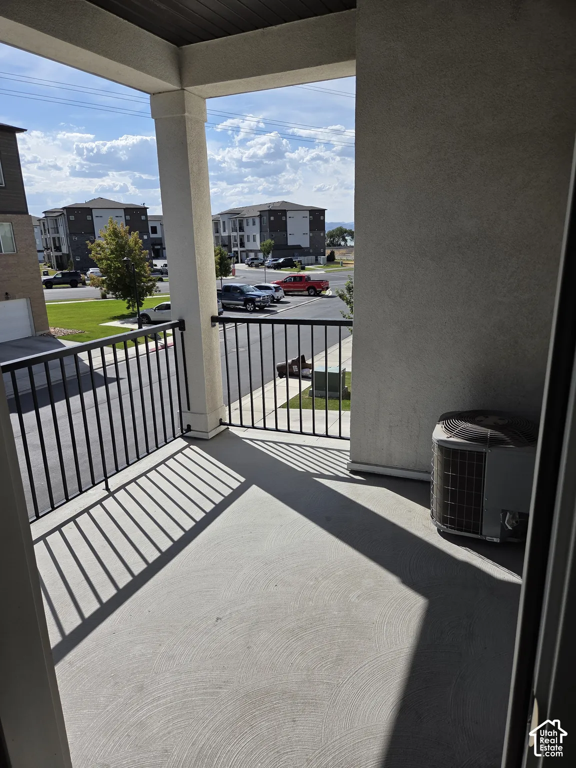 Private balcony featuring a concrete surface, black metal railing, and stucco exterior walls