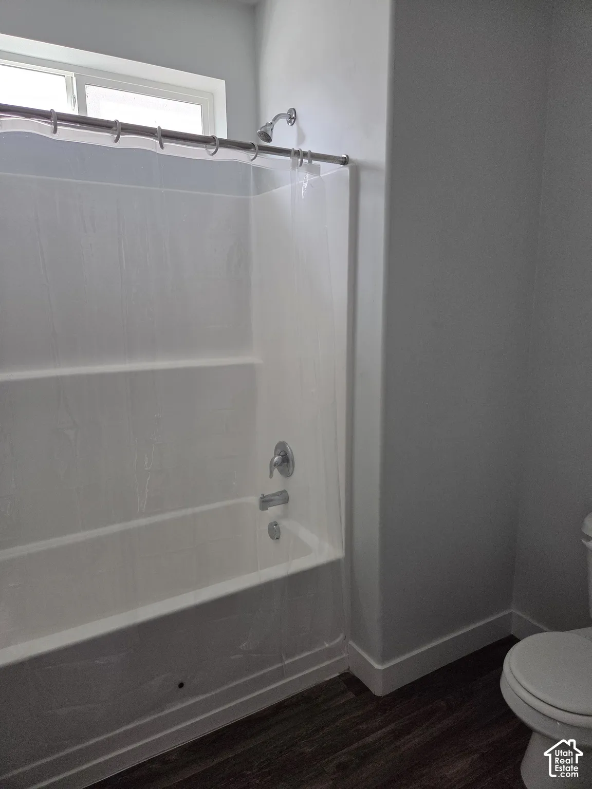 Bathroom featuring a white tub with shower, chrome fixtures, and a high window